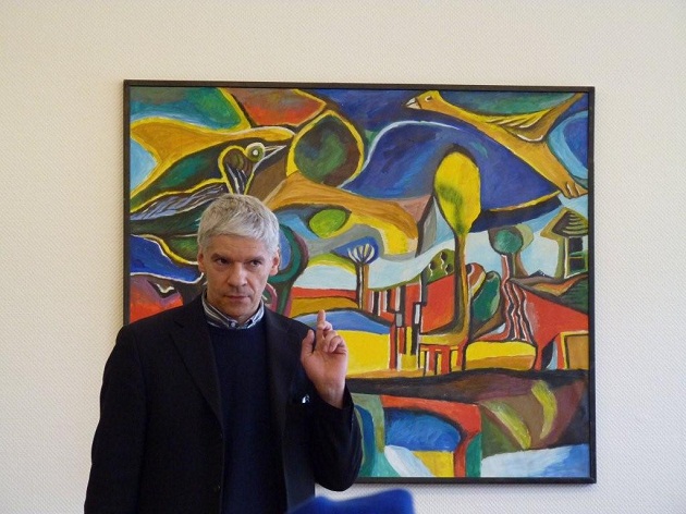 Pianist und Komponist Dominique Goris vor einem der Gemälde, die er am Flügel begleitete
