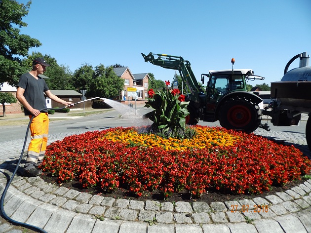 Ein Mitarbeiter des Baubetriebshofs der Gemeinde Henstedt-Ulzburg bewässert die Blumen auf einer Verkehrsinsel